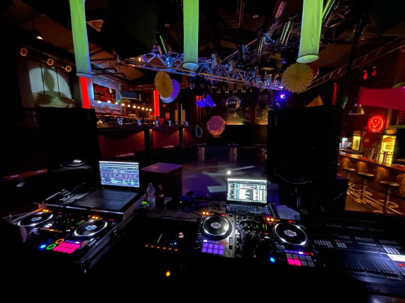 DJ-Pult mit zwei CDJs und Mixer in einem Club vor leerer Tanzfläche