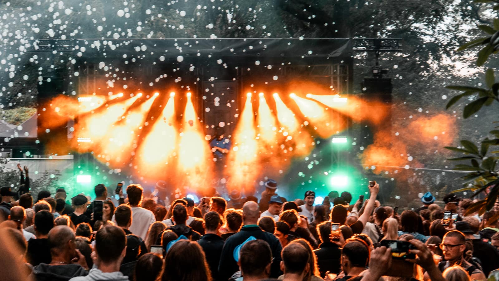 Open-Air-Bühne mit auffächernder Lichtshow in warmen Orangetönen vor jubelndem Publikum