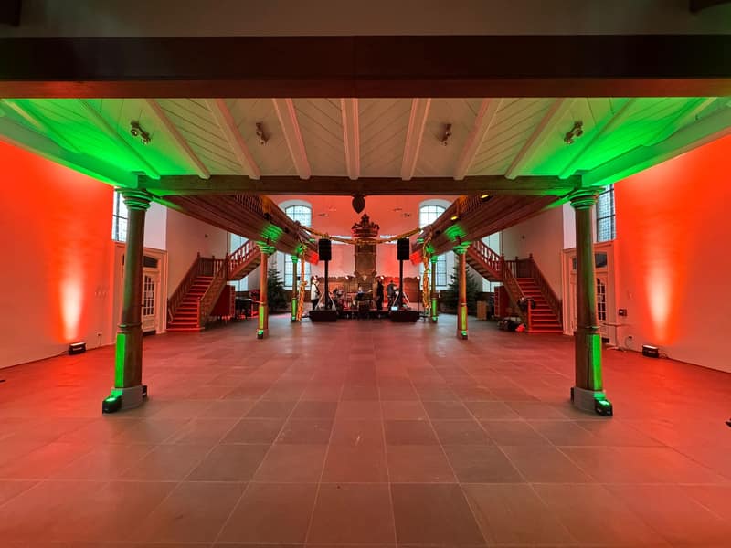Historischer Festsaal mit roter und grüner Akzentbeleuchtung und Live-Band